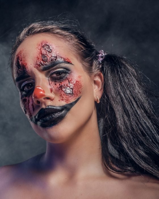 Evil psycho clown makeup looks especially creepy in a smoke over dark background.